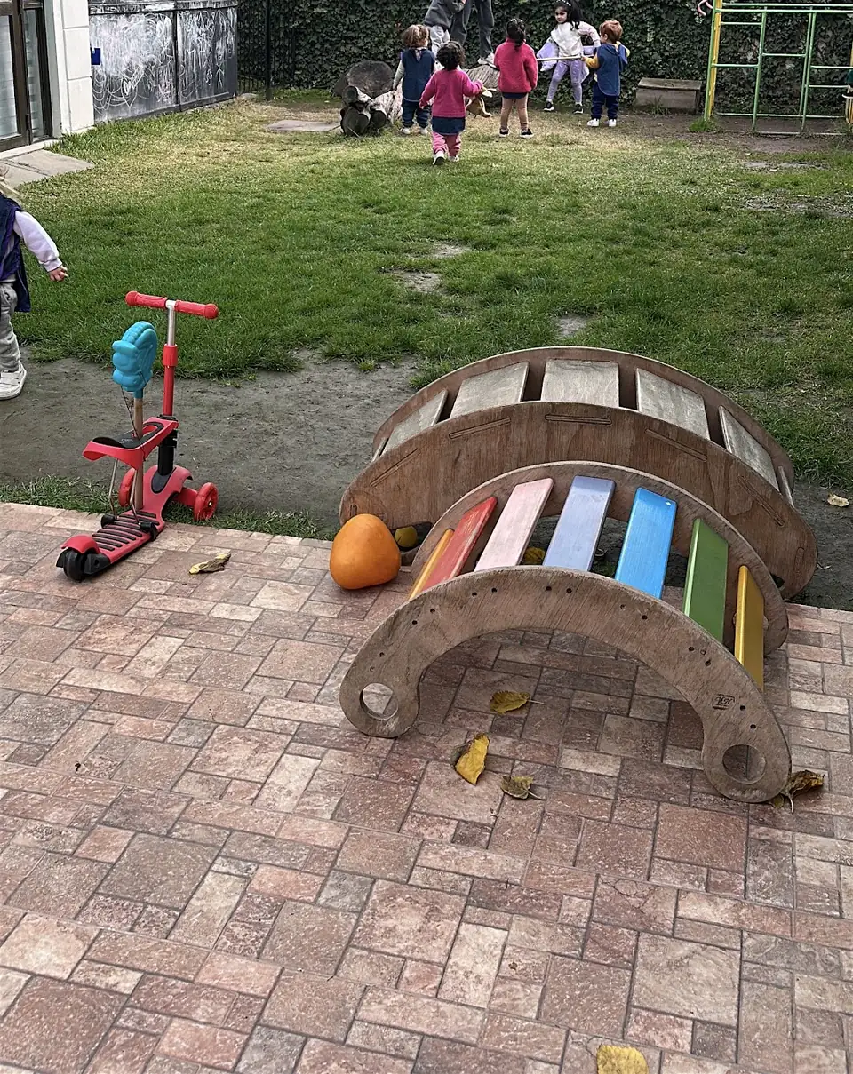Jardín con pasto, scooter y balancín de madera de colores