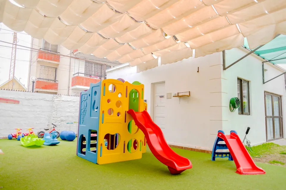 Patio techado de Nanai con juegos y pasto sintético