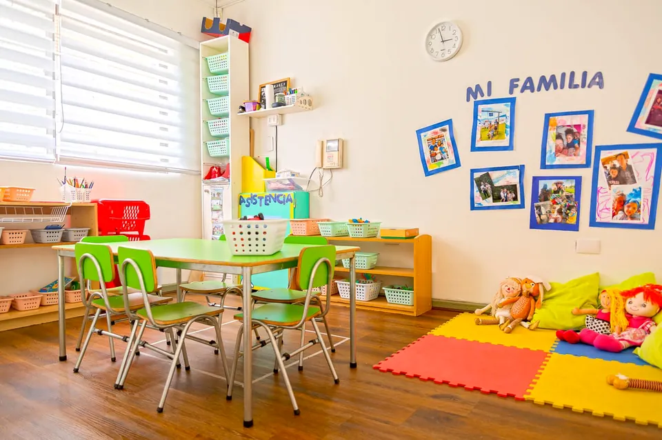 Sala con mesas verdes y el mural «Mi familia»